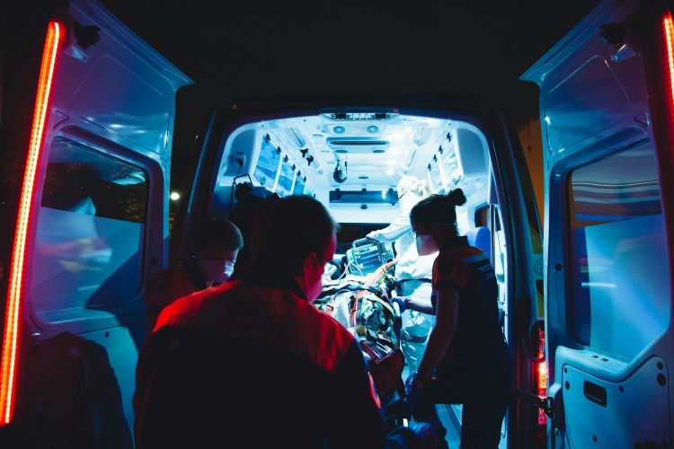 The back of an ambulance with paramedics attending to a casualty