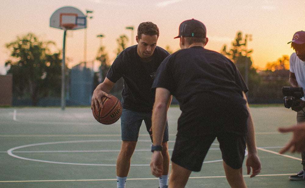 Two men playing basketball at sunset