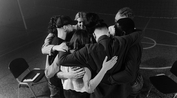 Black and white photo of a group of patients hugging at a drug and alcohol rehab in Lincoln