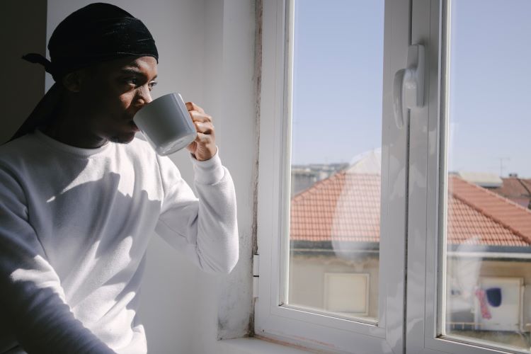 Man drinking tea and looking out a window at a drug and alcohol rehab in Durham