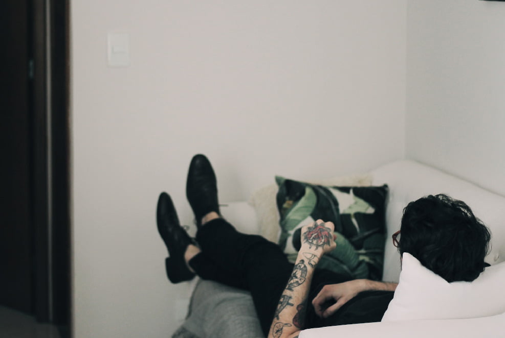 A tattooed man relaxing with his feet up on a sofa