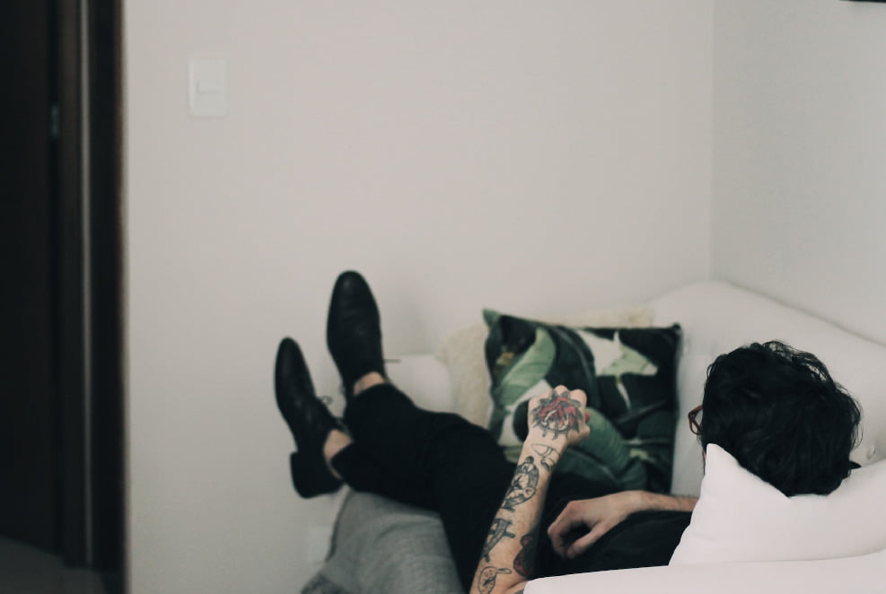 A tattooed man relaxing with his feet up on a sofa in Cumbria