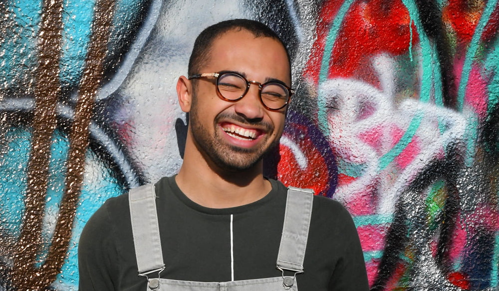 A man smiling with a graffiti background in Leeds