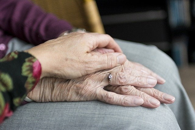 Older person and younger person holding hands at a drug and alcohol rehab in Gloucester