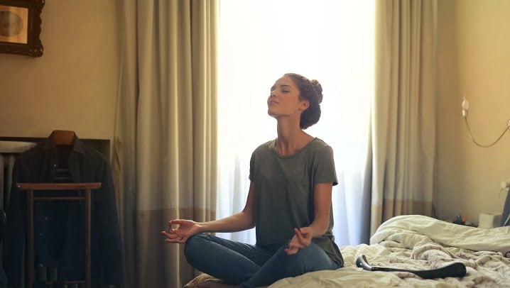 Person meditating on a bed at a drug and alcohol rehab in Hertfordshire