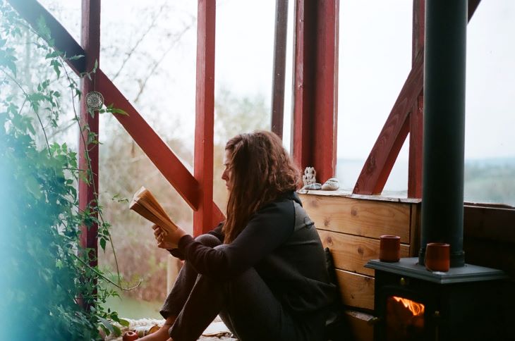 Person reading a book next to a fire at a drug and alcohol rehab centre in Milton Keynes