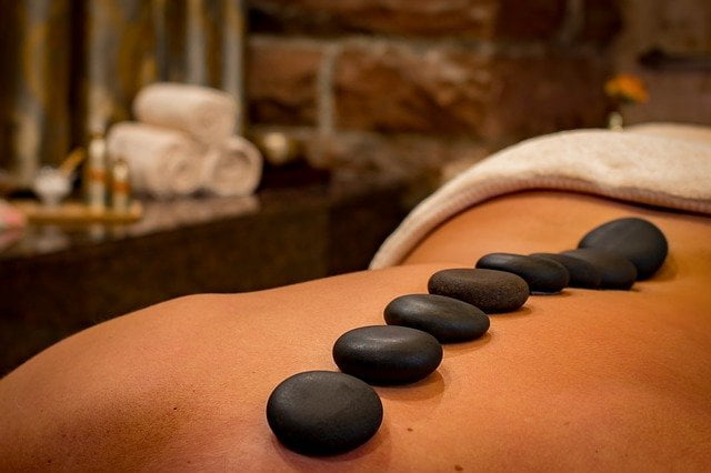 Person receiving a hot stone massage during a holistic therapy session at drug and alcohol rehab in Ipswich