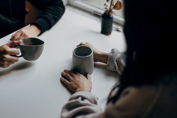 Two people drinking coffee and facing each other at a table in Bradford