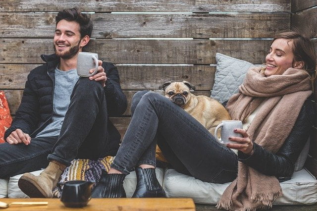 Two people drinking hot drinks and sat with a dog at a residential drug and alcohol rehab centre in Milton Keynes