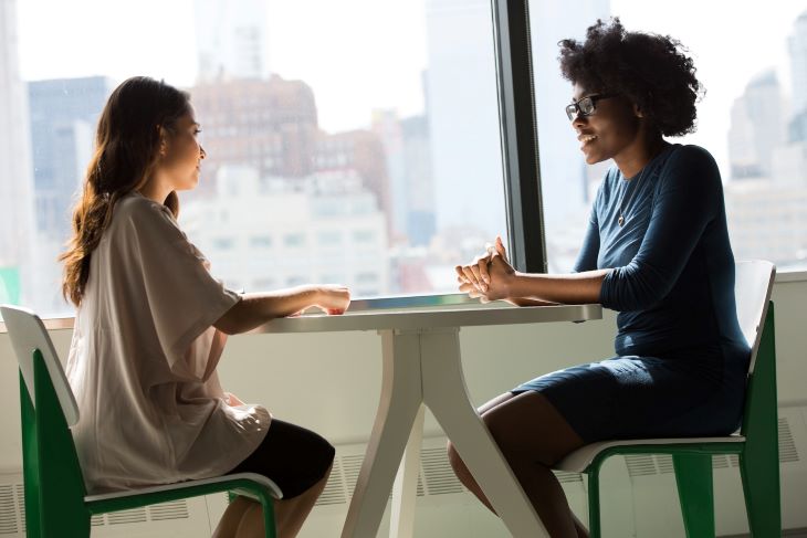 Two women sharing a serious conversation at a drug and alcohol rehab clinic in Durham