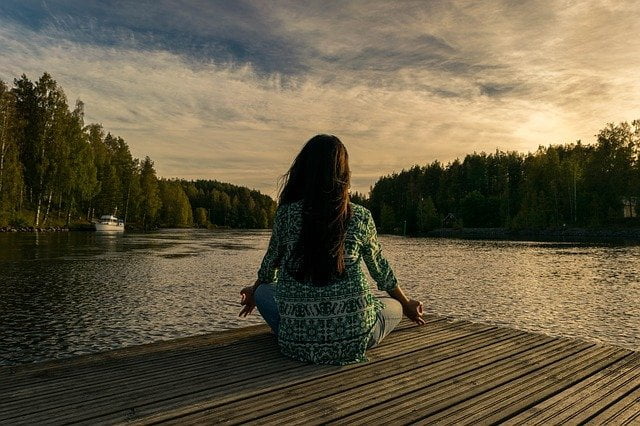 Woman meditating next to a lake at a drug and alcohol rehab clinic in Derby