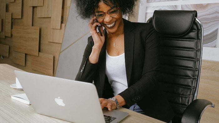 Woman typing on a laptop and speaking on a phone at a drug and alcohol rehab in Durham