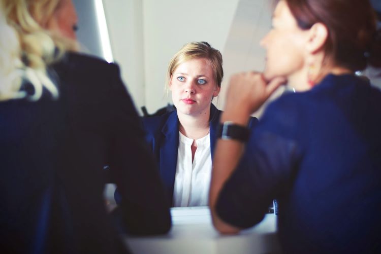 A woman in a blazer in meeting, looking deep in thought