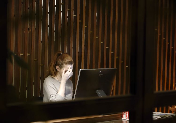 A woman covering her face at her desk in Cardiff