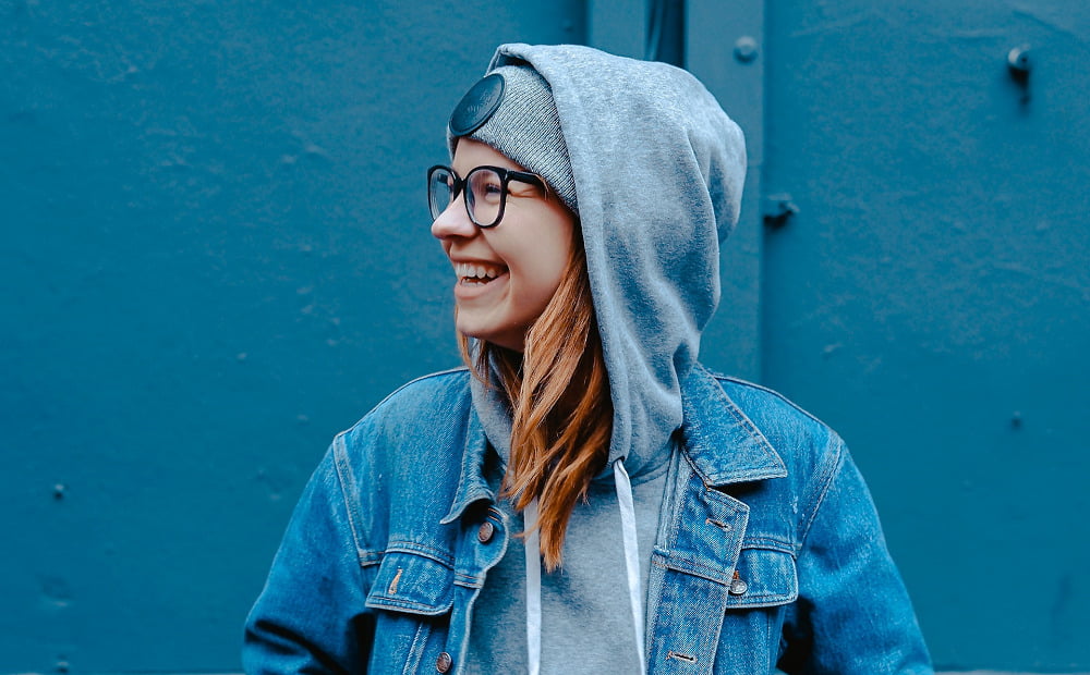A woman smiling in a hoodie and glasses