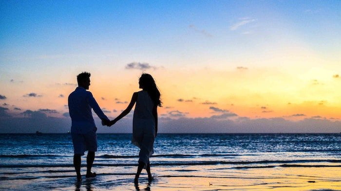 Couple holding hands on beach in Hampshire