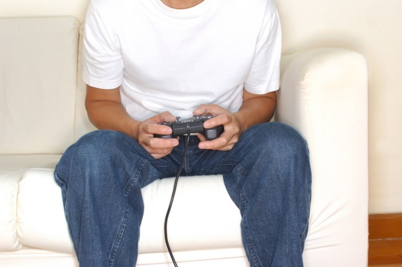 Man sat on a sofa suffering from video game addiction
