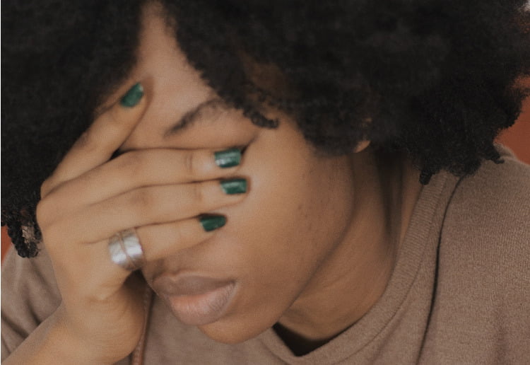 Woman with her hand over her eyes, looking sad