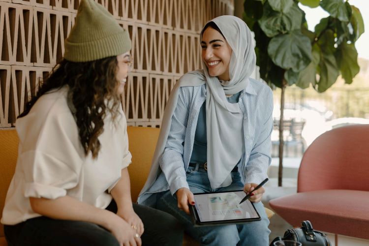 Two women looking at an ipad, smiling in Reading