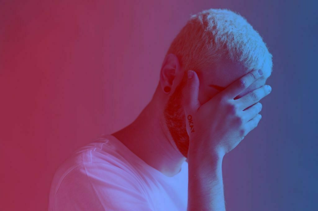 Depressed man covering his face red filter effect
