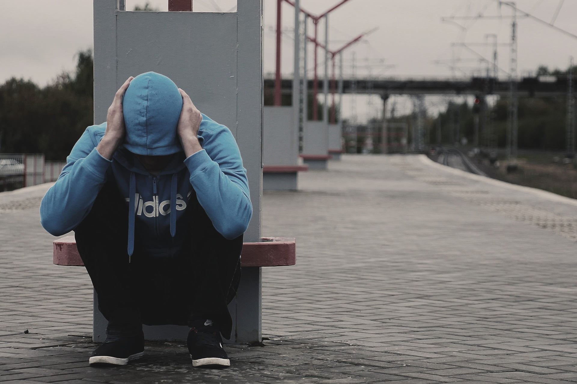 Man with hood up, head in hands