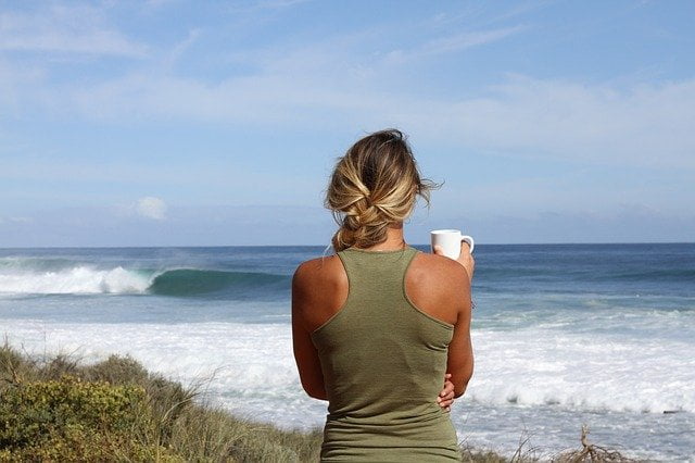 Woman drinking a coffee by the sea at a drug and alcohol rehab in Bedfordshire