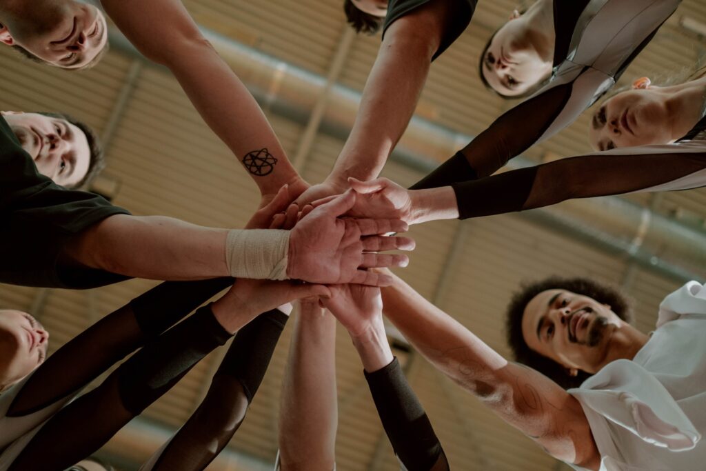 Group of people in a circle with their hands in the middle touching