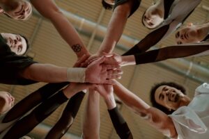 Group of people in a circle with their hands in the middle touching