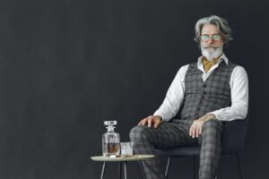 Man in suit sitting on stool drinking whiskey