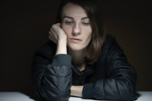 Young woman leaning on desk looking tired.