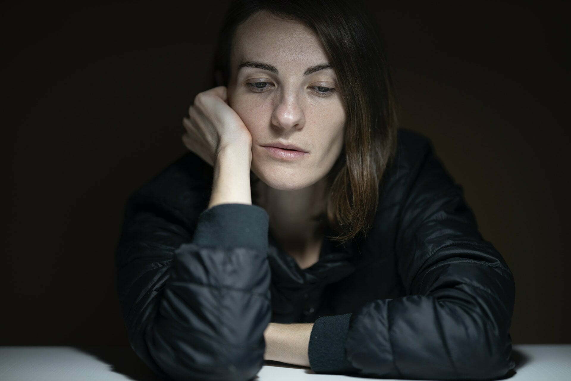 Young woman leaning on desk looking tired.