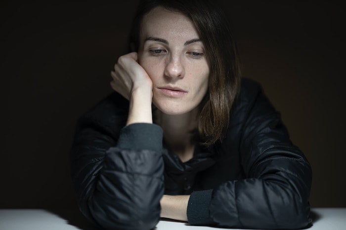 Young woman leaning on desk looking troubled