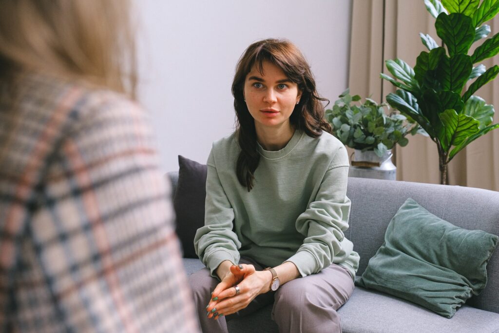 Young woman sitting on a sofa talking to a support worker in Coventry