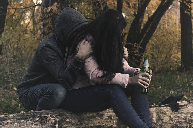 couple, one with hood up, and girl holding beer bottle