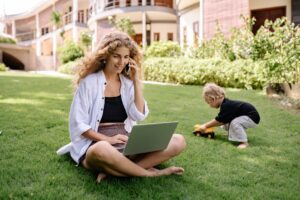 mother on the phone in the garden with toddler next to her