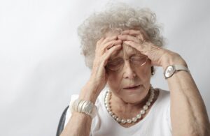 An old woman holding her head in distress