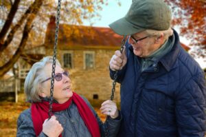 An elderly man and woman talking on the swings