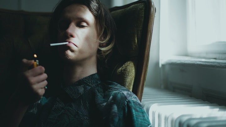 Man sat on a chair smoking a cannabis joint