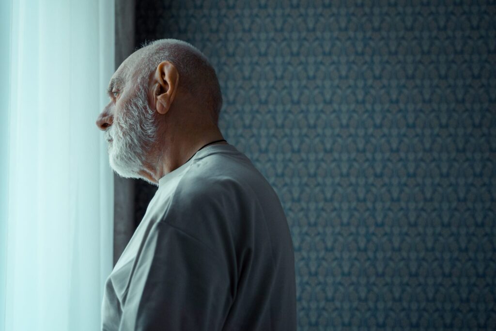 elderly man looking out window