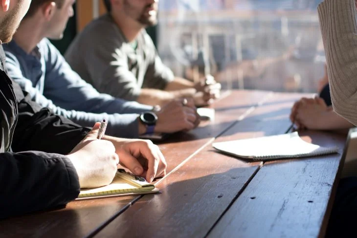 A group of people at a table with notebooks in Swansea