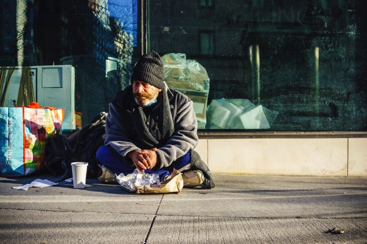 A homeless man sitting on the path