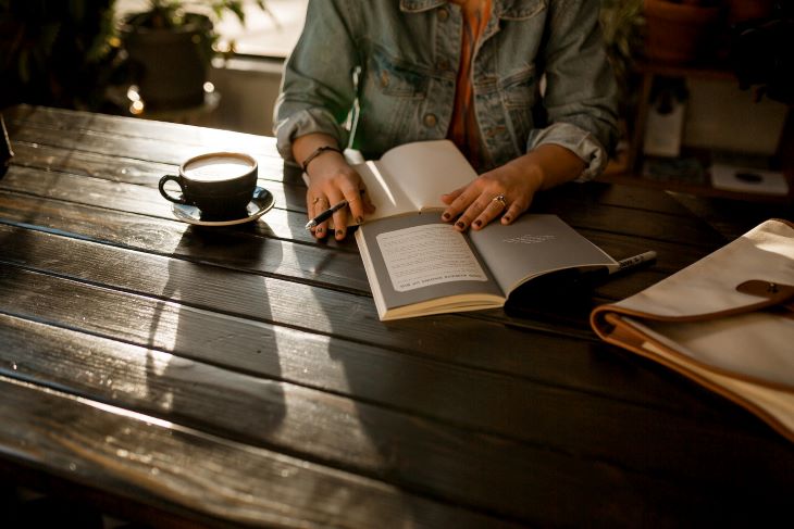 A woman with a book and a coffee, journaling in Somerset