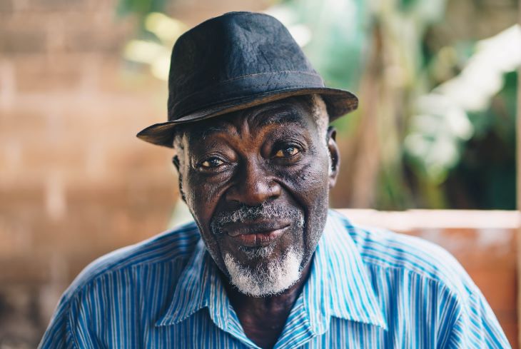 An elderly man wearing a hat, smiling