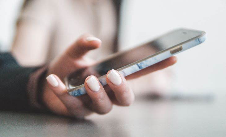 Woman with painted nails holding a mobile in Northumberland