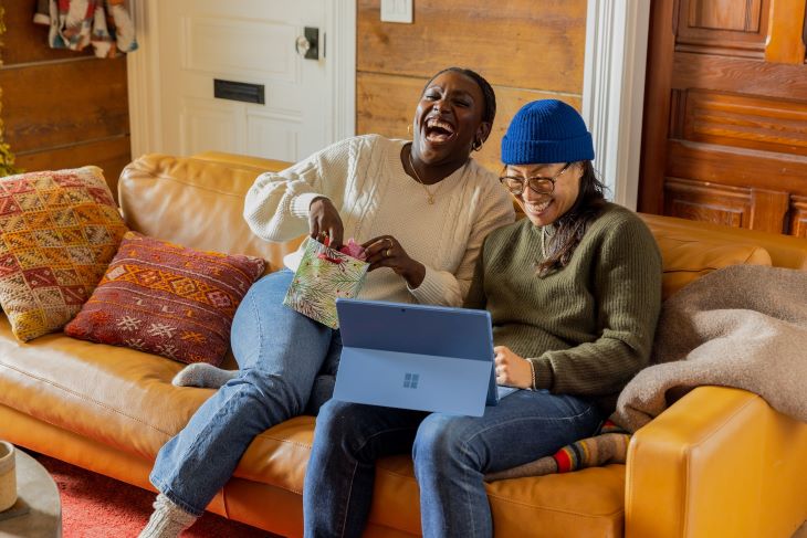 Two women laughing on a sofa.