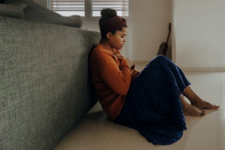 A woman sitting on the floor looking anxious