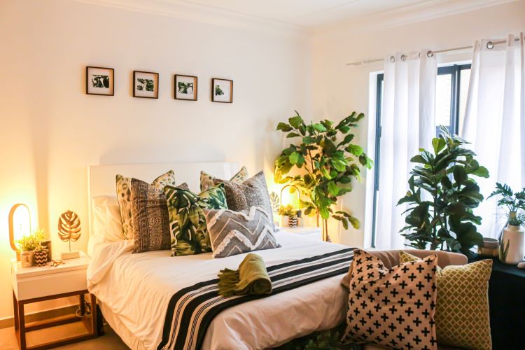 A bedroom with brown and neutral scatter cushions on the bed