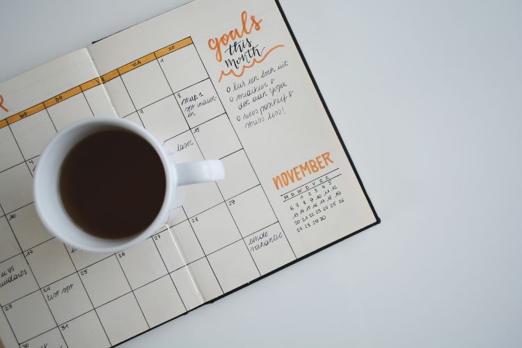 A calendar with goals set and a mug of coffee on top