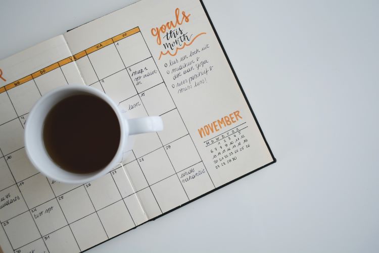 A calendar with goals set and a mug of coffee on top in Leeds