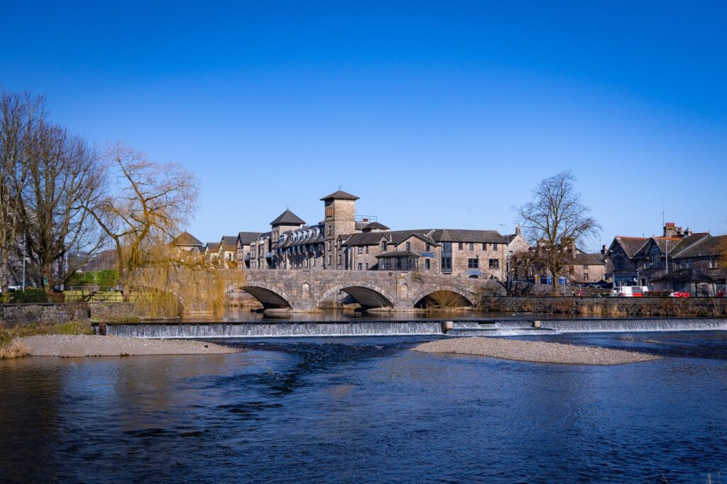 A brown concrete building near a body of water in Kendal